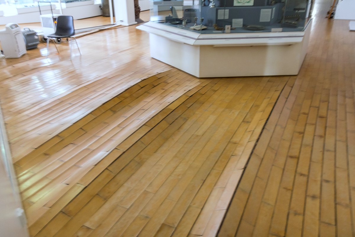 Suelo de parquet levantado y abombado en una sala, con las lamas separadas y curvadas